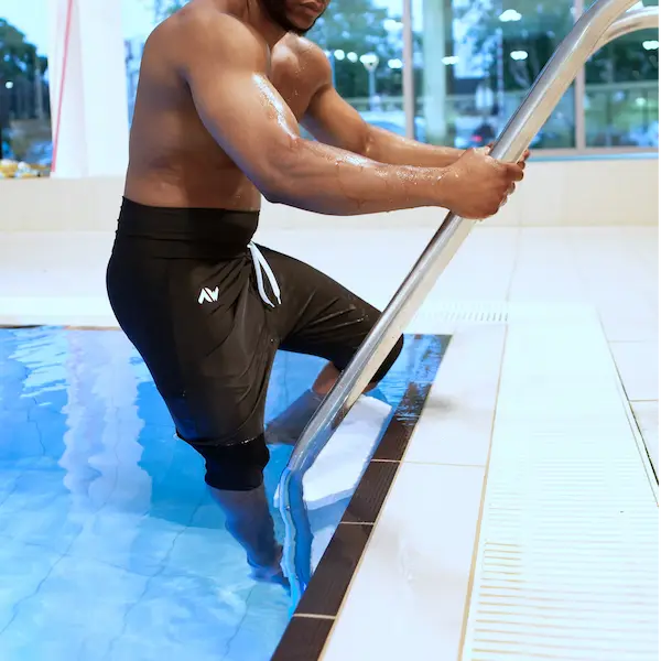 Un homme qui monte les marches d'une piscine avec un maillot de bain qui cache la awra de l'homme.